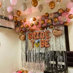 This image shows the full effect of the 'Bride to Be' party decoration in a room. The setup includes a balloon garland on the ceiling, a silver fringe backdrop with foil letters, and balloons scattered on the floor for a complete party look.