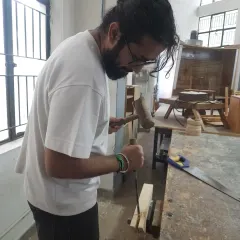 Mastering hand tools is essential for true craftsmanship. Here, a student uses a mallet and chisel to create a precise joint, a skill that offers a level of control that power tools cannot match.