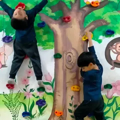 There's always a new way to climb. This angle shows the kids using different holds and techniques to challenge themselves on our indoor climbing wall, a highlight of our kids gym.