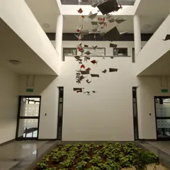 The central, multi-story atrium at Torishima Pumps. We designed this space to be the heart of the building, introducing natural elements with an indoor garden and a suspended art installation. This reflects our belief in biophilic design to enhance the workplace environment for employees.