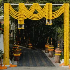 A vibrant entrance arch for a Haldi or Mehendi ceremony, constructed entirely from bright yellow marigold garlands. This cheerful and traditional design instantly sets a festive and joyful mood.