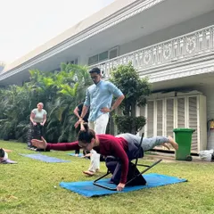 This student is practicing a variation of Virabhadrasana III (Warrior III) with the support of a chair. Using props helps build balance, strength, and confidence, making advanced poses achievable for everyone.