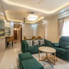 An inviting living area featuring an emerald green sofa that adds a pop of color. The space is designed for comfort and conversation, with a layout that connects seamlessly to the kitchen's breakfast bar and the dining area.