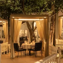 A glimpse of our outdoor dining area, where each table is a private corner. The warm lighting and surrounding trees create an enchanting atmosphere for a memorable night out.