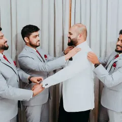 The groomsmen helping the groom with the final touches on his suit, a great candid moment of friendship and support.