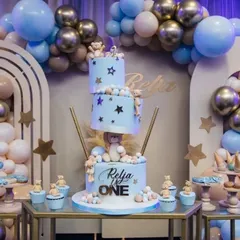 A detailed shot of the stunning three-tiered cake from the boho teddy bear party. The cake and cupcakes are perfectly integrated with the theme, featuring tiny bears, stars, and a matching color scheme.