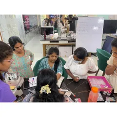 A trainer giving personalized guidance to a small group of students during a hands-on nail art session.