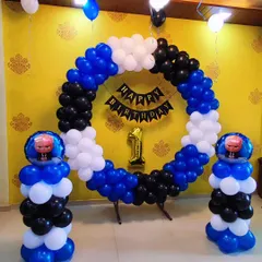 A "Boss Baby" themed first birthday party with a bold blue, black, and white color palette. The centerpiece is a circular balloon arch, complemented by balloon columns topped with Boss Baby foil balloons.