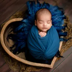 A simpler version of the pose, focusing purely on the baby's peaceful face and the beautiful textures of the wrap and wool layer.