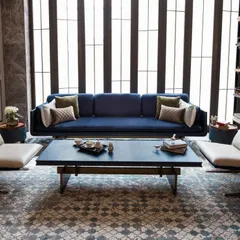 This living room setting demonstrates a meticulous balance of materials. A deep blue suede sofa is flanked by two cantilevered lounge chairs in a rose gold metal finish, creating a symmetrical and sophisticated arrangement.