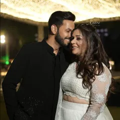 A beautiful moment between a couple dressed in custom Kaara. Her white lehenga features delicate floral appliqué on the sleeves and skirt, while his classic black sherwani has subtle matching embroidery, creating an elegant, coordinated look.