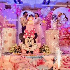 The perfect shot! This photo captures the happy family during the cake-cutting moment at a Minnie Mouse-themed birthday party, complete with sparklers and a stunning balloon and cake table setup.