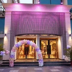 A beautiful pastel balloon arch at the entrance of a modern banquet hall. This welcoming decoration sets the tone for the celebration inside, with soft lighting enhancing the colors.