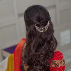 A close-up of a half-up hairstyle for an Engagement look, featuring soft waves and a beautiful multi-layered traditional hair pin.
