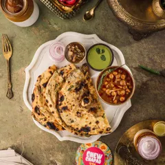 A top-down shot capturing a classic North Indian meal. I used a dark, moody style to highlight the rich textures of the garlic naan and the deep colors of the chole, creating a rustic and soulful image for Chew Chapad's menu.