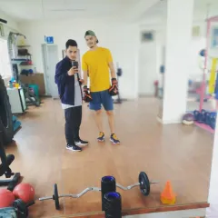 With a client in the gym. The open layout provides ample space for personal training sessions, with access to free weights and other equipment.