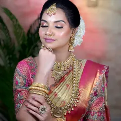 A serene South Indian bride with her eyes closed, showcasing the soft, glowing makeup and the intricate details of the layered temple jewellery.