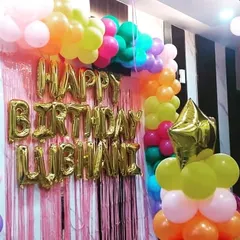 This angle shows the balloon arch over the foil curtain backdrop. The mix of vibrant latex balloons and star-shaped foil balloons adds a festive touch to the at-home birthday party decor.