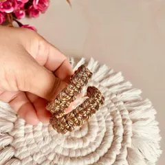 A close-up of the golden macrame hoop earrings. The intricate knotting gives them a unique texture and style.