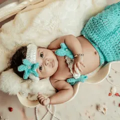 A treasure from the sea. This little mermaid theme is one of my favorites, using a knitted tail and a seashell prop to create a magical ocean scene.