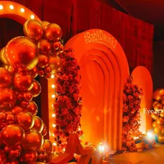 A closer view of the Bollywood themed party decor, highlighting the metallic red balloon garland and the lit marquee arch. This setup is designed to be a high impact photo opportunity for guests.