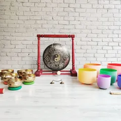 My shala is home to a wide array of sound healing instruments. This setup includes a collection of hand-hammered Tibetan bowls, colorful chakra-tuned crystal bowls, and a Yin-Yang gong, each with its own unique voice and healing properties.