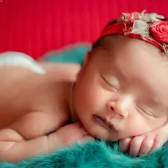 A pop of color can make a simple portrait stand out. This baby is posed on a vibrant red and teal background, highlighting their beautiful skin tone.