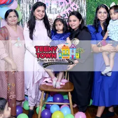 A precious moment from Reyanshi's 4th birthday party. The birthday girl, wearing a crown, is surrounded by her family in front of a festive balloon backdrop.