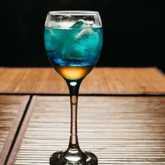 A layered cocktail in a tall glass, expertly lit to show the different colors. This is a great example of the moody and sophisticated beverage photography you can book.
