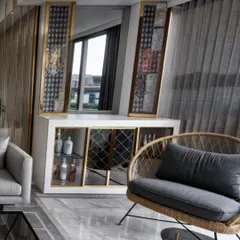 This image captures a custom-designed bar and console unit in a Goregaon West residence. The piece features white and gold accents, mirrored surfaces, and integrated lighting, serving as a functional and elegant focal point in the living room.