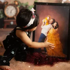 A touching moment from a first birthday shoot. The birthday girl looks at a framed portrait of her family, a beautiful symbol of love.