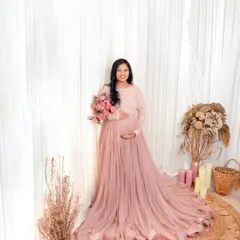 A mother-to-be surrounded by soft light and flowers. This portrait in a beautiful pink gown captures the love and anticipation for the new life to come.