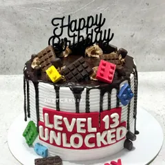 A fun "Level 13 Unlocked" cake perfect for a teenage gamer. This design combines a chocolate drip with edible Lego blocks and a bold gaming-themed message.
