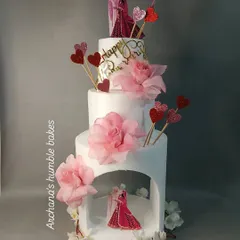 A modern and romantic anniversary cake with a unique arch structure. The design features delicate sugar flowers and couple toppers.
