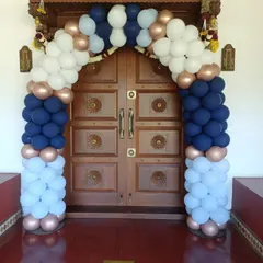 A classic balloon arch in navy blue, white, and rose gold, perfectly framing a traditional wooden door for a stylish welcome.