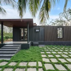 This project showcases how a modern prefab home can blend perfectly with nature. The combination of dark corrugated steel and warm wood-panel cladding creates a sophisticated look, while the large glass doors connect the indoor space with the surrounding landscape.