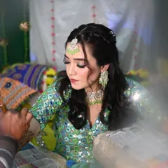 A candid moment during the mehendi application. The bride's makeup is soft and pretty, with a mint green maang tikka matching her outfit.