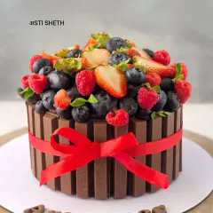 This is my classic KitKat Cake, a chocolate cake surrounded by crispy KitKat bars and topped with a generous amount of fresh, exotic berries like strawberries, blueberries, and raspberries.