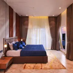 This luxurious bedroom exudes timeless elegance with its refined decor. The rich satin drapes frame a large window, offering a beautiful view and creating a serene haven for rest.