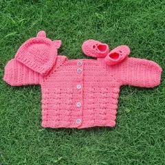 This complete three-piece baby set in a lovely coral pink is ready for a new home. It includes a textured bubble-stitch sweater, little slip-on booties, and a matching hat with cute bear ears.