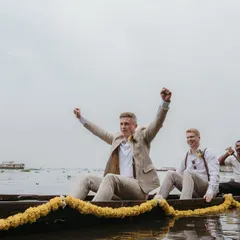 The groom and his groomsmen make a grand entrance on a boat in the beautiful Kerala backwaters, a unique experience for a destination wedding.