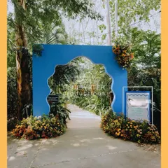 A bold and beautiful entrance arch in a striking blue, framed by colorful marigolds, setting a playful and welcoming tone for a summer Haldi.