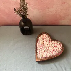 A lovely shot of my heart-shaped dough bowl candle, filled to the brim with delicate pink and white wax flowers. It's a true statement piece, perfect for adding a touch of romance and fragrance to any room.