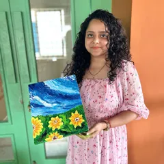 A participant proudly holding her vibrant sunflower painting, created using palette knives for a rich, textured effect.