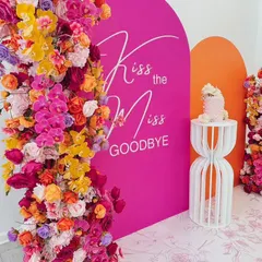 "Kiss the Miss Goodbye" with this bold and colorful backdrop. The vibrant floral arrangements against the hot pink arch create a fun and energetic atmosphere perfect for a bachelorette celebration.
