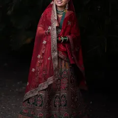 A radiant bride in a magnificent red and gold lehenga. The detailed embroidery and velvet dupatta make this a truly regal choice for a wedding day.