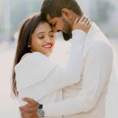 A tender moment between a couple dressed in white, captured in the warm, soft light of a city afternoon.