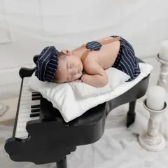 Sweet dreams on a grand piano. This creative newborn setup combines elegance and innocence, with the baby sleeping peacefully on the keys.