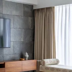 We believe in creating harmony between different materials. Here, the cool, rugged texture of the slate stone TV wall is balanced by the warmth of the wooden media console and the soft, printed fabric of the daybed.