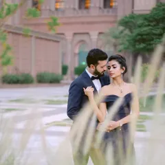 An intimate embrace amidst the lush greenery of the palace grounds. The soft focus and natural framing create a dreamy, romantic portrait.
